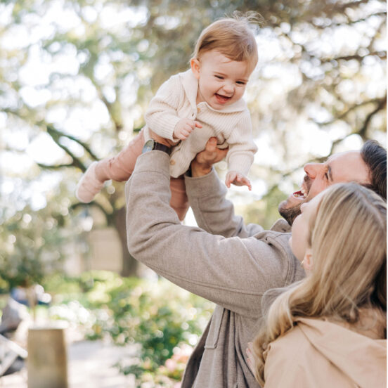 Child laughs as parents playfully raise him into the air